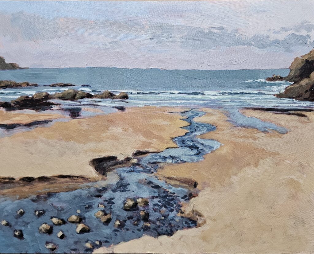 Stream running to the sea with rocks on either side of beach and horizon line.